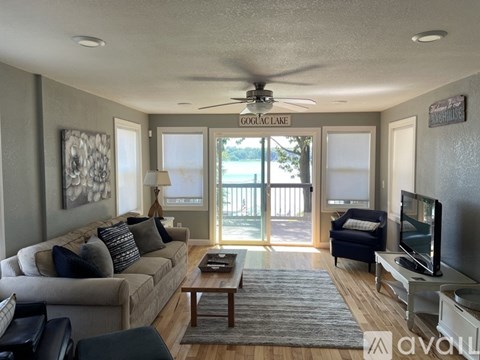 A living room with a couch, a coffee table, a television, and a fan.