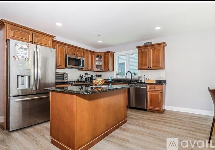 A kitchen with wooden cabinets and a stainless steel refrigerator.