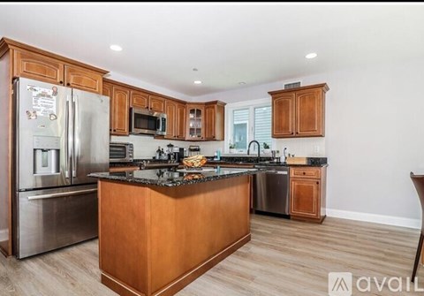 A kitchen with wooden cabinets and a stainless steel refrigerator.