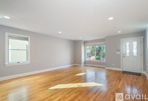 A spacious room with wooden flooring and a large window.
