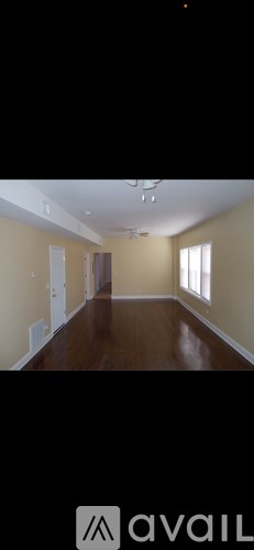 A room with wooden floors and a window on the right side.