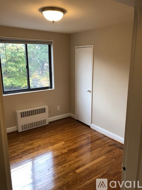 A room with a window, a door, and a radiator.