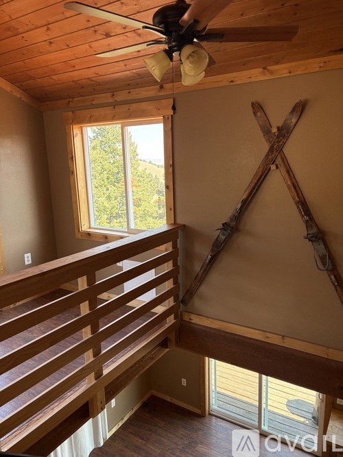 A room with a ceiling fan and a window with a view of trees.