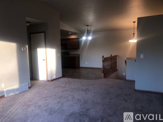 A spacious living room with a carpeted floor and a ceiling fan.