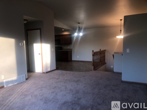 A spacious living room with a carpeted floor and a ceiling fan.