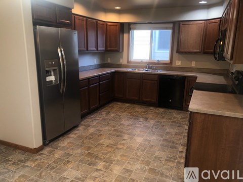 A kitchen with a black refrigerator and brown cabinets.