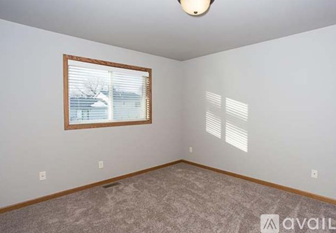 A room with a window and a carpeted floor.