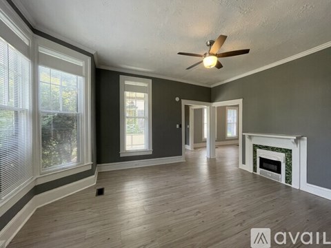 A spacious room with a fireplace and a ceiling fan.
