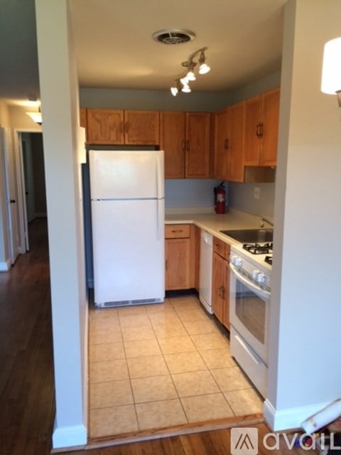 A kitchen with a white refrigerator and wooden cabinets.