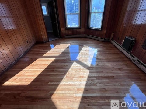 A room with wooden flooring and a window letting in sunlight.