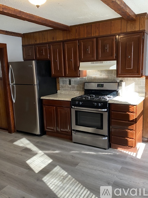 A kitchen with wooden cabinets and a black fridge.