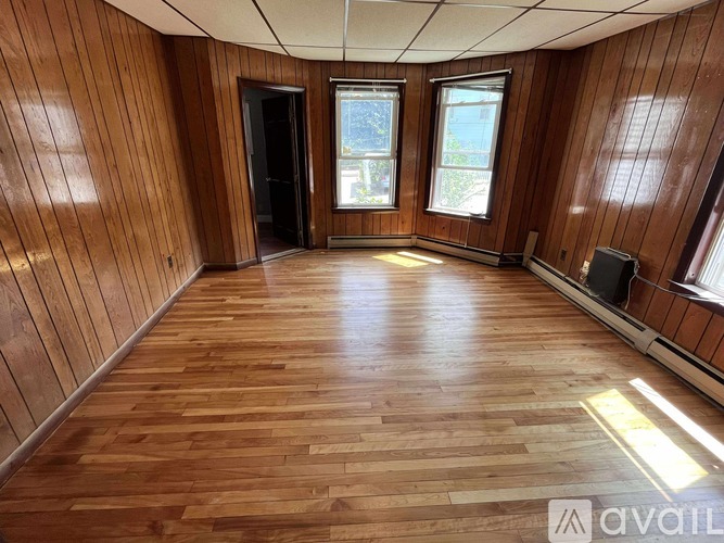 A room with wooden floors and a window showing a view of a building.