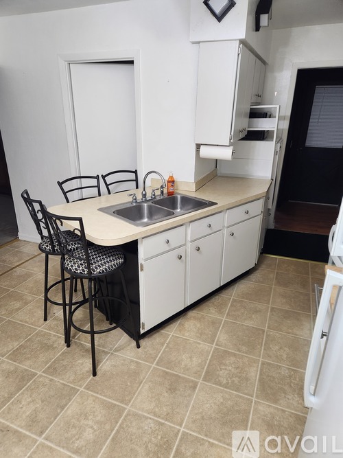 A kitchen with a sink, stove, and bar stools.