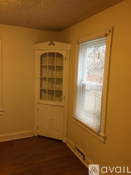 A room with a white cabinet and a window with blinds.