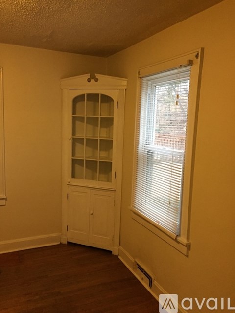 A room with a white cabinet and a window with blinds.