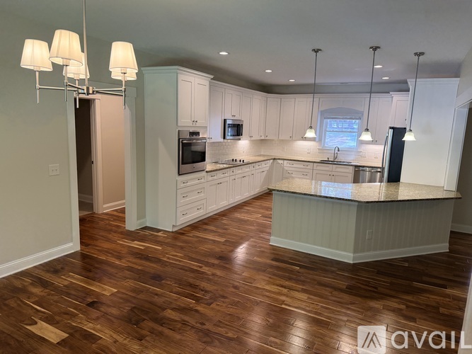 A kitchen with white cabinets and a wooden floor.