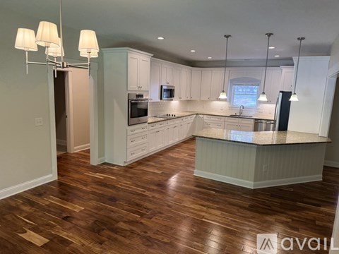 A kitchen with white cabinets and a wooden floor.
