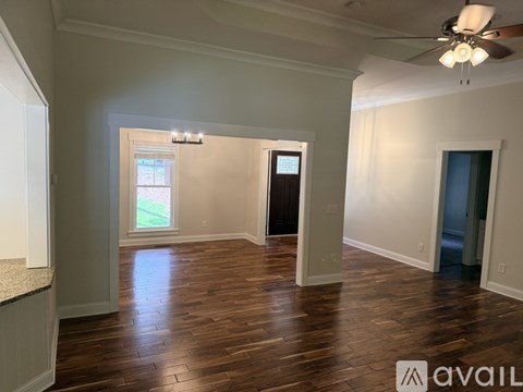 A spacious room with wood flooring and a ceiling fan.