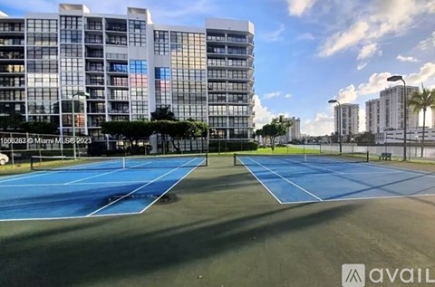 A tennis court is located in front of a tall building.