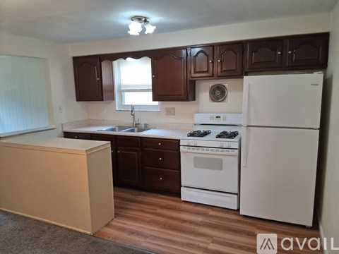 A kitchen with white appliances and brown cabinets.