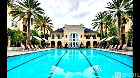 A large swimming pool in front of a building with palm trees.