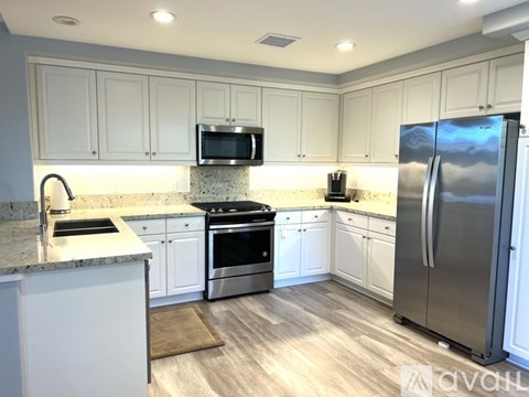A kitchen with white cabinets and a stainless steel refrigerator.