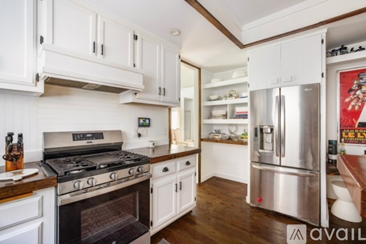 A kitchen with white cabinets and a stainless steel refrigerator.
