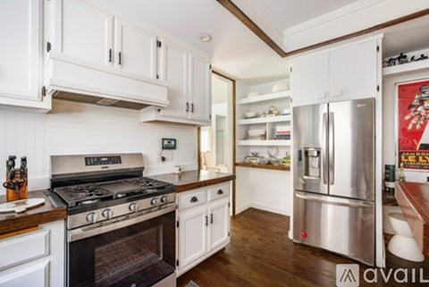 A kitchen with white cabinets and a stainless steel refrigerator.