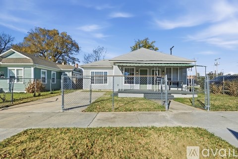 A house with a grey roof and a white fence is for sale.