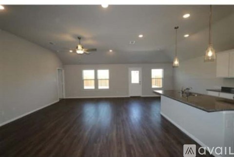 A spacious room with wooden floors and a kitchen area.