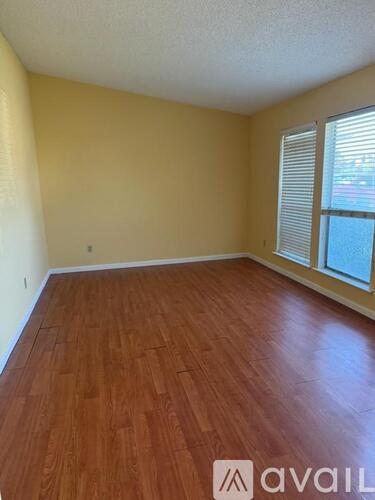 A room with wooden flooring and a window with blinds.