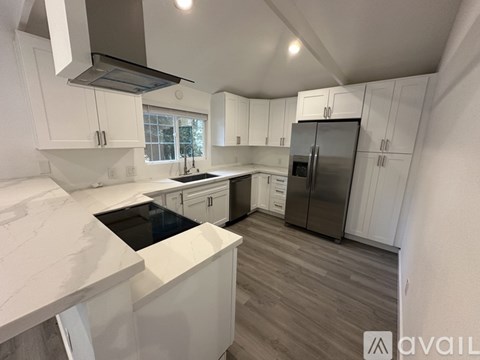 A kitchen with white cabinets and a marble countertop.