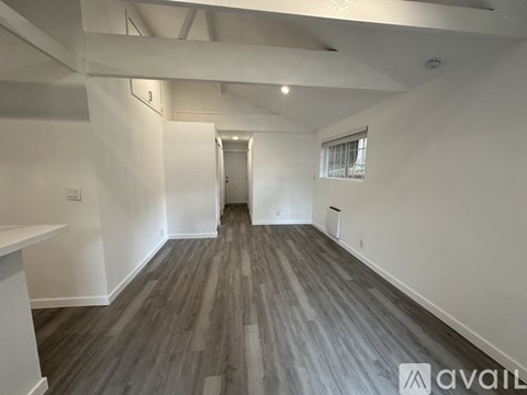 A spacious room with wooden flooring and white walls.