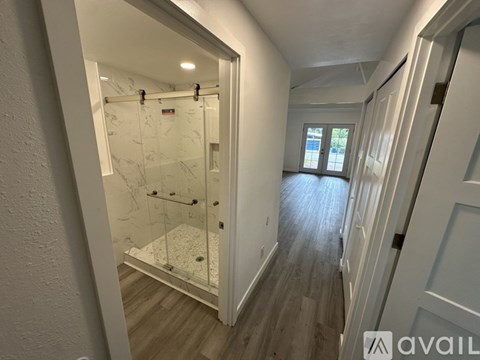 A bathroom with a walk-in shower and a wooden floor.