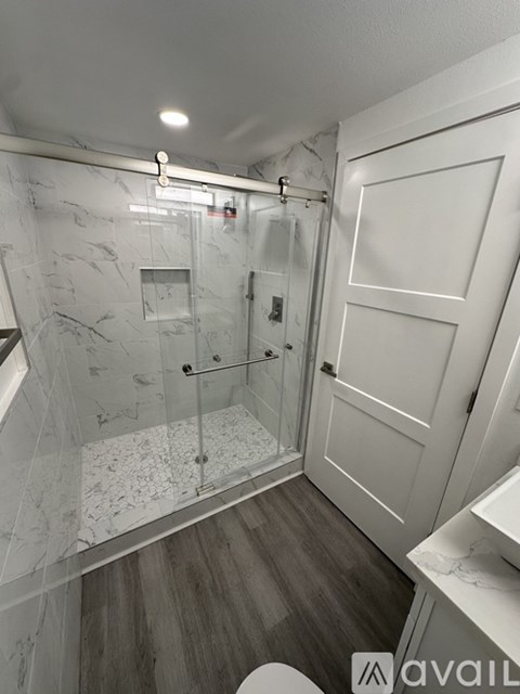 A bathroom with a marble wall and a walk-in shower.
