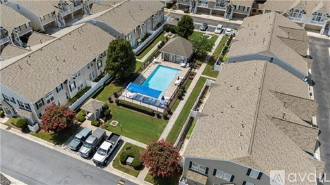 A bird's eye view of a residential area with houses, a swimming pool, and parked cars.