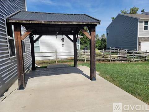 A wooden pergola with a metal roof is situated in a backyard.