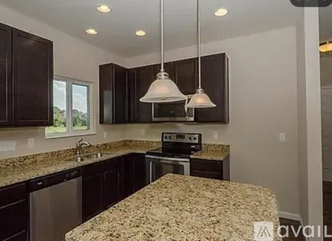 A kitchen with granite countertops and dark brown cabinets.