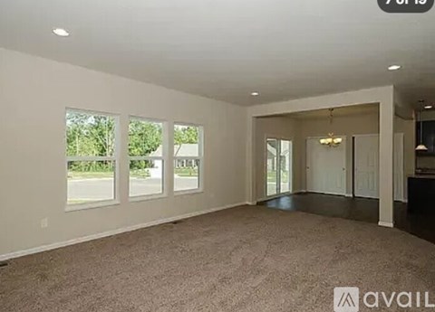 A spacious room with a carpeted floor and large windows.