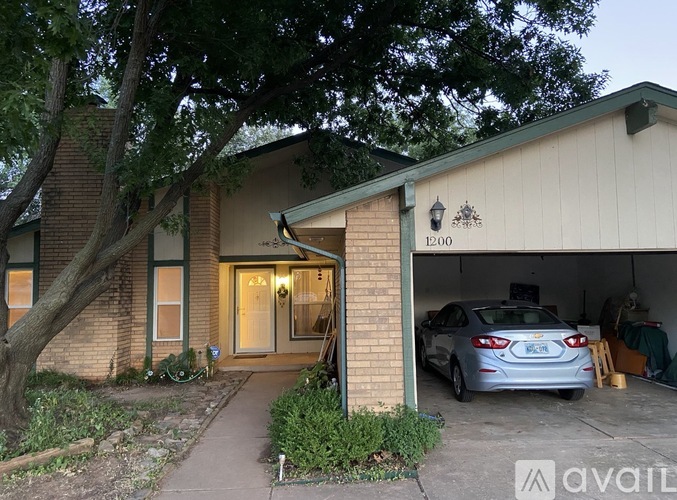A house with the number 1200 on the front wall and a car in the garage.