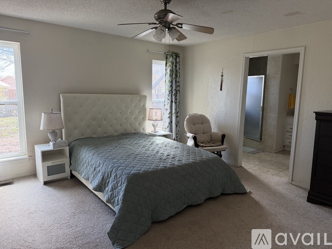 A bedroom with a large bed and a ceiling fan.