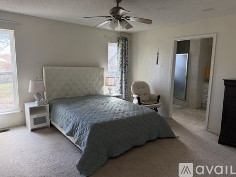 A bedroom with a large bed and a ceiling fan.
