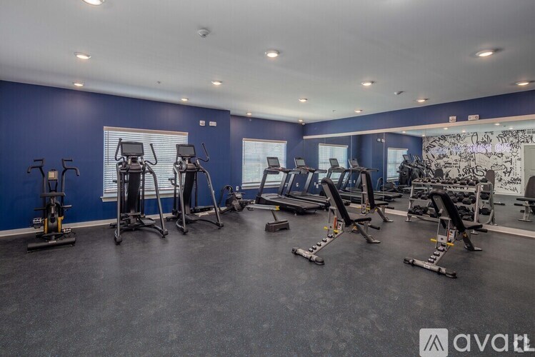 A gym with various exercise equipment and a large mirror on the wall.
