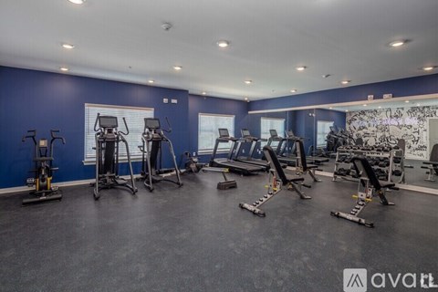 A gym with various exercise equipment and a large mirror on the wall.
