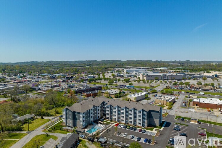 A large apartment complex is surrounded by a parking lot and other buildings.