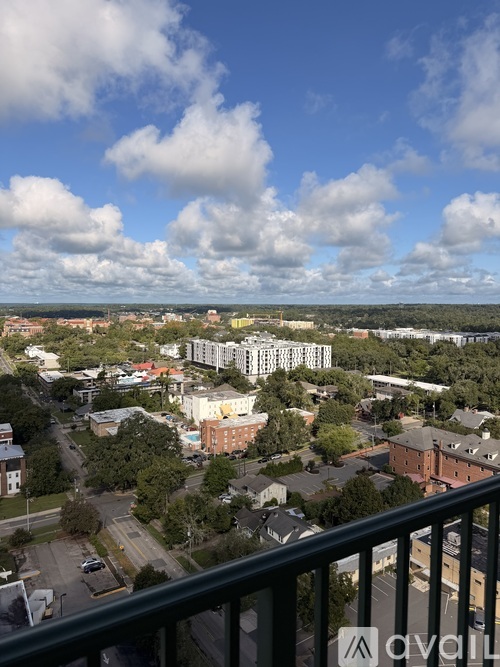 A view from a balcony overlooking a city with buildings and trees.