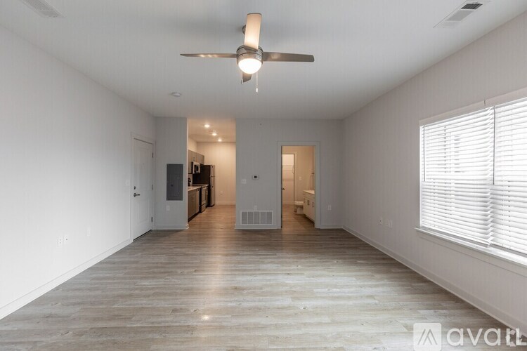 A spacious room with wooden flooring and a ceiling fan.
