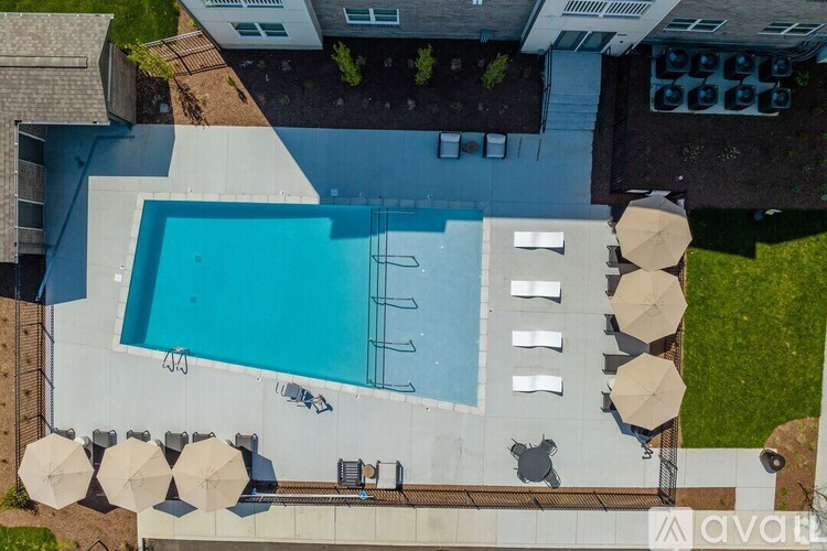 An outdoor swimming pool surrounded by lounge chairs and umbrellas.
