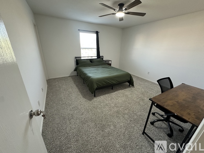 A bedroom with a bed, desk, and chair.
