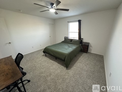 A bedroom with a bed, chair, and table.
